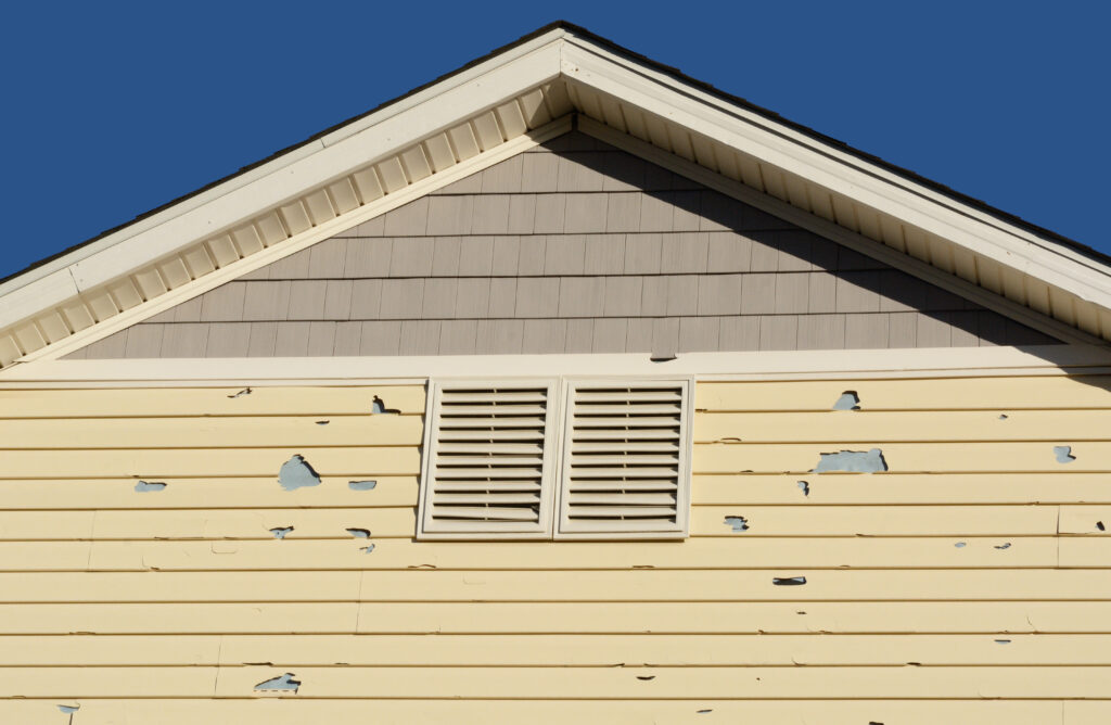 Holes in exterior siding in home from damage by hail storm